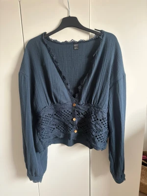 Mörkblå blus med spetsdetaljer - Supersnygg mörkblå blus från Shein med virkade spetsdetaljer över midjan och knappar framtill. Djup v-ringning med spetskant och långa ärmar med resår vid ärmslut. Perfekt för en trendig och festlig stil.  Frakt betalar man själv