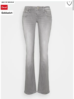 Grå bootcut jeans med stretch - Snygga grå bootcut jeans med klassisk femficksdesign och knappgylf. Jeansen har en lätt tvättad look och är tillverkade i ett stretchigt material för extra komfort. Perfekta för dig som gillar en avslappnad men trendig stil.