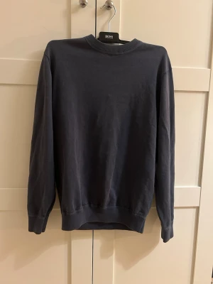 Mörkblå sweatshirt från Doppelgänger - En stilren blå sweatshirt med en utvättad look från doppelgänger med rund halsringning och ribbade muddar vid ärmslut och nederkant. Tröjan har en enkel och klassisk design som passar till det mesta. Perfekt för dig som gillar en clean och tidlös look.