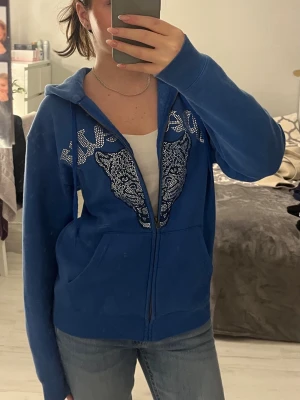 Blå tröja med diamanter  - Säljer nu min älskade blåa tröja med ett tryck av diamanter/rhinestones! Storlek S och har en jättefin passform för både killar och tjejer. Fortfarande fint skick och INGA diamanter har lossnat! (Nypris: ca 800kr)