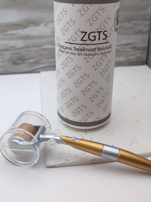 Oanvänd ZGTS dermaroller med guldfärgat handtag - En dermaroller från ZGTS med guldfärgat och silverfärgat handtag. Rollern har ett cylinderformat huvud med tunna nålar och skyddande plastlock. Perfekt för microneedling och hudvård. Levereras i originalförpackning. Jag har aldrig använt den. Jag öppnade den och ställde fram den för att jag skulle använda den med serum, men jag har aldrig fått tummen ur så det kommer ju inte hända. Annars är det nog ett fantastiskt sätt att få det mesta ur sitt serum!