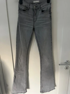 Grå bootcut jeans från Gina Tricot - Säljer ett par snygga grå bootcut jeans från Gina Tricot. Jeansen har klassisk femficksmodell, Dom är mid waist och är i storlek 32 Dom har dock ett liten slitning ibak se bild 3 