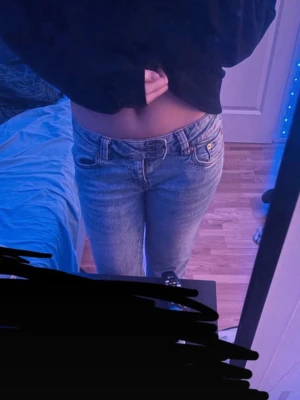 Ljusblåa jeans med mönstrade fickor  - Säljer ett par ljusblåa jeans med raka ben och snygga mönster på bakfickorna. Jeansen har klassisk femficksmodell, normal midja och är tillverkade i ett denimtyg. Perfekta för dig som gillar en avslappnad men ändå trendig stil.