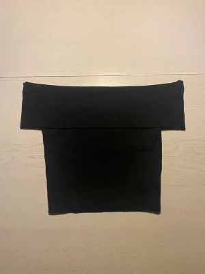 Svart offshoulder tubtopp - Trendig svart offshoulder tubtopp från ginatricot med bred kant upptill. Sitter tight och väldigt skönt material. Säljer då den inte kommer till användning.💕