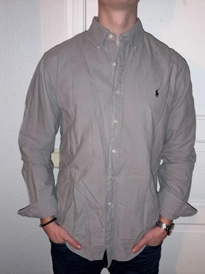 Grå skjorta från Ralph Lauren - Grå skjorta från Ralph Lauren i storlek L.  Fint skick till ett bra pris. Nypris: 1995kr. Mitt pris: 349kr. Vid frågor eller funderingar, tveka inte att höra av dig.