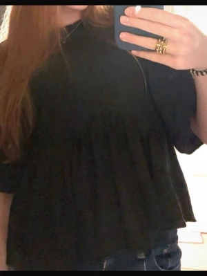 Svart volangblus med puffärm - Trendig svart blus från Pieces med puffiga långärmar och volangdetaljer. Blusen har en rund halsringning och är tillverkad i ett strukturerat tyg som ger en snygg look. Perfekt att styla med jeans eller kjol för en cool outfit.