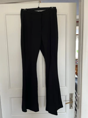 Svarta utsvängda kostymbyxor - Säljer ett par svarta kostymbyxor med utsvängda ben från Pernilla Wahlgren design.