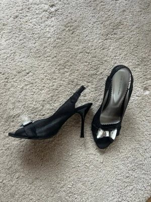 Svarta vintage klackar med rosett  - Jättefina classy svarta miniklackar med öppen tå från Gibi Collection. Glas rosett framtill och bekväma att gå i💕💕 Pris går att diskutera