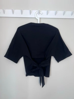 T-shirt från Nelly - Populär t-shirt från Nelly med öppen rygg med knytning. Använd fåtal gånger!