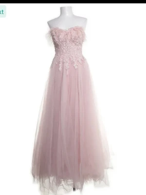  balklänning -  ljusrosa balklänning med axelbandslös design och spetsdetalj upptill. Kjolen är lång och vid i flera lager tyll. Perfekt för bal eller speciella tillfällen. Märket är Ömur Inn. Strl S. Passade mig i längden förra året när jag var 170 cm. Pris går att diskutera🥰