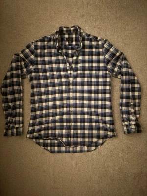 Blårutig skjorta från Zara Man - Snygg blårutig skjorta från Zara Man i slim fit-modell. Skjortan har långa ärmar, klassisk krage och knäppning framtill. Tillverkad i bomull och passar perfekt för en stilren look.