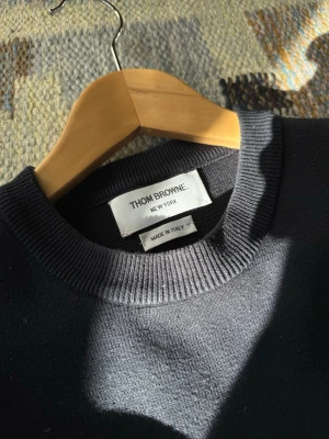 Mörkblå Thom Browne Tröja - THOM BROWNE Milano Stitch Crew Neck - Navy Storlek 3 (herr), men har krympt i tvatten och motsvarar nu ungefär en storlek 2. Tröjan är i bra skick, men lite nopprig. En extra knapp medföljer :)