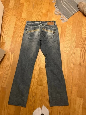 Blå bootcut/ straight jeans från Replay - Snygga blå bootcut jeans från Replay med slitningar och ljusare partier på både fram- och baksida. Klassisk femficksmodell med detaljerade bakfickor och läderpatch i midjan. Perfekta för en avslappnad och trendig look. Det står storlek 26 men skulle säga att de är i 32, de är även uppsydda eftersom de var för långa för mig. För mer bilder samt mått mm så är det bara att skriva till mig!💕