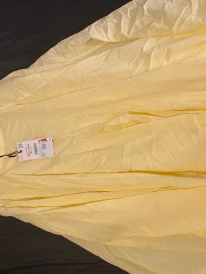 Ljusgul långkjol från zara - Säljer en ljusgul långkjol från zara i tunn och luftig bomull. Kjolen har en flowy och vid passform som ger en riktigt somrig vibe. Perfekt att styla med en enkel topp och sneakers för en chill look.