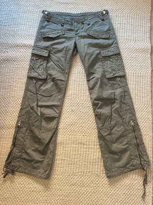 Lågmidjade cargobyxor med nitar  - Raka ben, dragkedjor vid bensluten och snörning längst ner. 100% bomull.