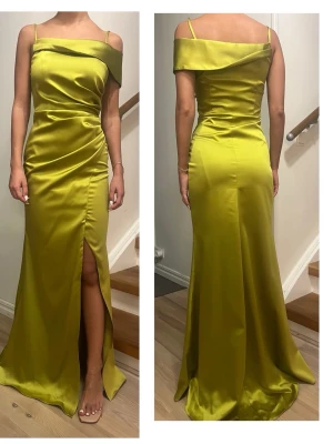 Elegant Gul-Grön Satin festklänning - Oanvänd  - En festklänning i ett glansigt satintyg som ger en lyxig känsla och framhäver figuren på ett smickrande sätt.  Nypris: 4500kr Säljer för 700kr Aldrig använt!!! Pris kan diskuteras 