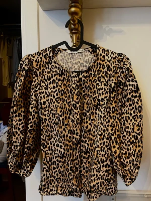 Leopardmönstrad blus från Zara - Säljer en leopardmönstrad blus från Zara med puffiga långärmar och rund halsringning. Blusen har en luftig passform men ändå figursydd kring midjan och knappar framtill. Materialet är lätt och känns skönt mot huden, perfekt för att sticka ut i mängden.