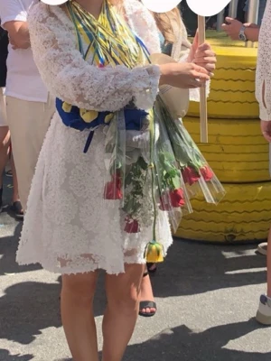  Vit  spetsklänning med långa ärmar - Superfin vit kort spetsklänning med långa ärmar och fyrkantig ringning. Blommigt spetsmönster och är perfekt för student eller sommarens festligheter. Sitter snyggt i midjan och har en lätt utsvängd kjol.