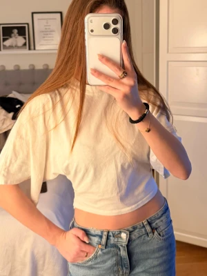 Vit croppad t-shirt - Säljer en enkel och stilren vit croppad t-shirt med korta ärmar. .