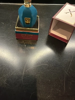 Xerjoff Eau de Parfum blå/guld - Lyxig parfym från Xerjoff i en elegant blå flaska med gulddetaljer och sammetliknande yta. Kommer i en vinröd och guld kartong med blått band. Tillverkad i Italien och utstrålar exklusivitet och stil.