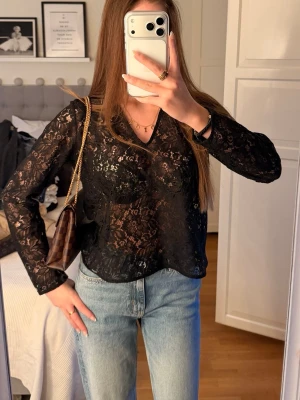Svart spetsblus med v-ringning - Snygg svart blus i  spets med v-ringning och långa ärmar. 