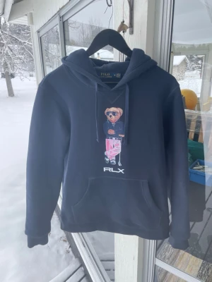Polo bear hoodie - Mörkblå polo bear RLX hoodie i fint skick. Står storlek M på lappen men skulle säga att den sitter mer som S. Bara att skriva vid fundering.