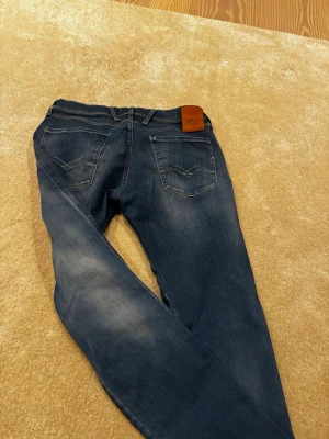 Blå jeans från Replay  med raka ben - Snygga blå jeans från Replay  med raka ben och klassisk femficksmodell. Jeansen har diskreta slitningar framtill och bakfickor med dekorativa sömmar. Tillverkade i ett mjukt denimtyg som ger en skön passform. L32