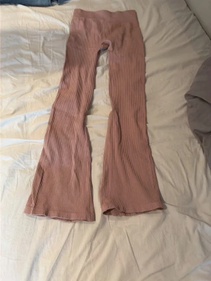 Rosa träningsbyxor med utsvängda ben - Säljer ett par ljusrosa ribbade träningsbyxor med utsvängda ben. Är från lager 157 i storlek 150/160. Endast provade 