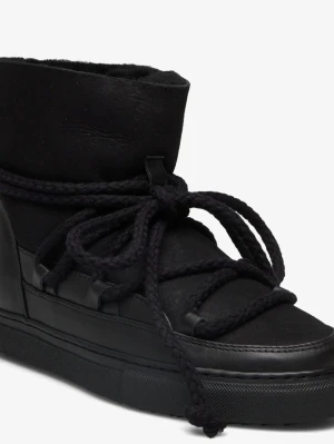 Svarta moon boots från Inuikii - Säljer ett par svarta moon boots från Inuikii med högt skaft och grova snören som snörning runt hela skon. Tillverkade i en mix av mocka och läder med en robust sula. Perfekta för kalla dagar när du vill ha både stil och värme.