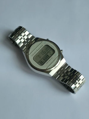 Citizen Quartz digital klocka silver - Digital armbandsklocka från Citizen Quartz med klassisk rund urtavla och digital display. Klockan har ett stilrent silverfärgat armband i rostfritt stål och en slimmad design som ger en retrovibe. Perfekt för dig som gillar tidlös och enkel stil. Klockan är vintage och är ifån 70/80-tal och passar för både män och kvinnor