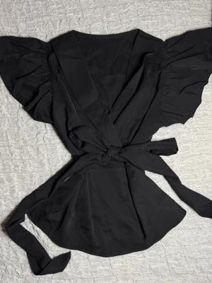 Svart blus med knytband  - Skit snygg svart blus med avtagbar knytband i midjan.