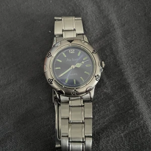 Aile Sport silverfärgad klocka - Stilren klocka från Aile Sport med silverfärgat metallarmband och rund urtavla. Urtavlan är blå med tydliga markeringar och lysande visare. Klassisk design som passar till många stilar.