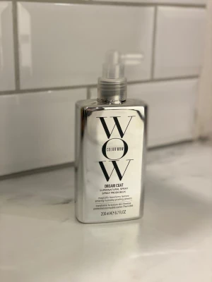 Color Wow Dream Coat spray 200ml - Color Wow Dream Coat Supernatural Spray i en silvrig, rektangulär plastflaska med pump. Produkten är en fuktresistent spray som hjälper till att släta ut och skydda håret mot friss. Flaskan rymmer 200 ml och har en modern, spegelblank finish med svart text.
