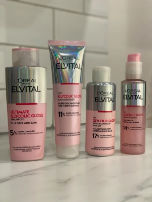 L'Oréal Elvital Glycolic Gloss set - Säljer ett set med L'Oréal Paris Elvital Glycolic Gloss: schampo, balsam, leave-in serum och glansspray. Produkterna har rosa och silverfärgade förpackningar och innehåller glykolsyra för extra glans och vård till håret.
