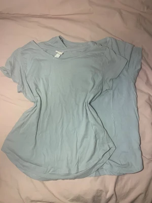 Ljusblå basic t-shirt från H&M - Två ljusblå basic t-shirts från H&M i mjuk bomull. Klassisk rund halsringning och korta ärmar, perfekt för en enkel och clean stil. Passformen är normal och materialet känns skönt mot huden. Snygga att matcha med jeans eller shorts.