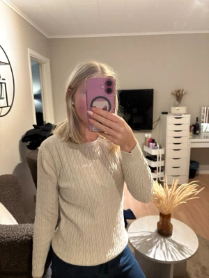 Beige kabelstickad tröja - Säljer en beige kabelstickad tröja med rund hals och långa ärmar. Tröjan har ett klassiskt flätmönster och är perfekt för att hålla dig varm under kyliga dagar. Passar dig som gillar stilrena och tidlösa plagg.