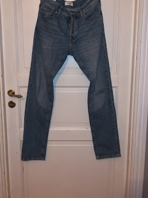 Blå tapered jeans från Jack & Jones - Säljer ett par klassiska blå jeans från Jack & Jones, modell Tapered/Mike. Jeansen har en avsmalnande passform och fem fickor. Perfekta för en avslappnad och stilren look. Materialet är denim i bomull.