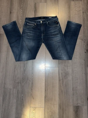 Mörkblå raka jeans från replay  - Snygga mörkblå jeans från replay med raka ben och klassisk femficksmodell. Jeansen har slitningar och tvättade detaljer framtill för en trendig look. Tillverkade i bomull med en skön passform och knappgylf. Perfekta till vardagsstilen.
