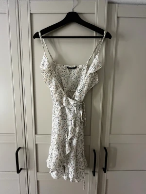 Blommig omlottklänning  - Söt vit omlottklänning från SHEIN med blommigt mönster i blått och beige. 