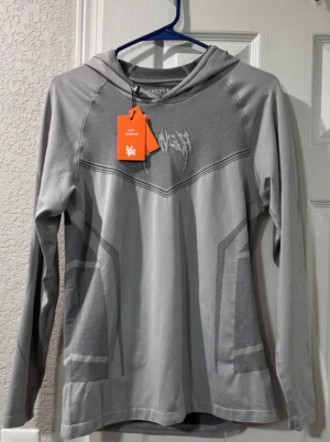 Grå compression hoodie från Young la - Grå compriession hoodie från young la. Tröjan har luva och är långärmad. tillverkad i ett mjukt, stretchigt material som passar perfekt för träning och aktiva dagar. Vid frågor elelr intresse är det bara att skriva