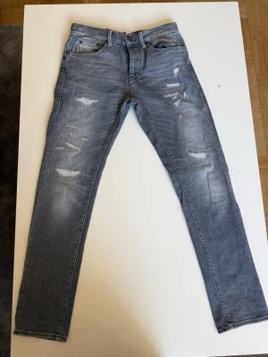 Grå slitna slim fit jeans från Herrlicher - Säljer dessa sjukt snygga jeansen. Snygga grå slim fit jeans med slitningar och distressed detaljer på framsidan. Säljer pga dom är för små, bara att höra av dig vid funderingar!