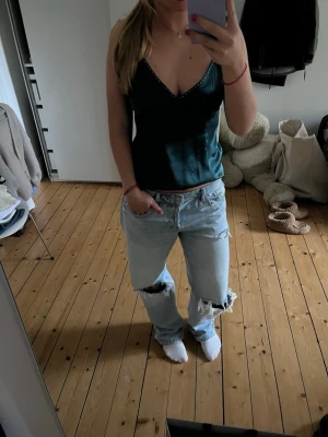 Mörkgrön silkestopp med glitterdetalj - Snygg mörkgrön silkestopp med coola detaljer. Toppen är v-ringad med smala justerbara axelband. Så najs och väldigt unik🌟Passar S-M