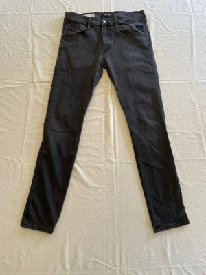 Svarta slim fit jeans från KappAhl - Snygga svarta slim fit jeans från replay med klassisk femficksdesign och knappgylf. Jeansen har smal passform och raka ben, perfekta till en trendig vardagslook. Materialet är mjukt och stretchigt för extra komfort.                        Jeansen har en liten fläck på vänsterbakfickan som man inte lägger märke till om man har på sig jeansen.                                                                 Tveka inte, hör av er vid intresse, frågor eller prisförslag!
