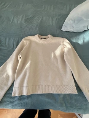 Beige stickad tröja Gina Tricot - Snygg beige stickad tröja från Gina Tricot med rund halsringning och ribbade muddar vid hals, ärmslut och nederkant. Enkel och stilren design som passar perfekt till jeans eller kjol. Mjuk och skön att ha på sig under kyliga dagar.