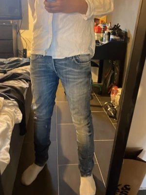 Slim fit jeans från Jack & Jones - Snygga ljusblå slim fit jeans från Jack & Jones med klassisk femficksdesign och slitna detaljer. Jeansen har normal midja och dragkedjegylf. Perfekta för en avslappnad och trendig look.