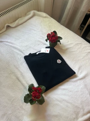 Svart Moncler tröja med logga - Snygg svart tröja från Moncler med rund halsringning och klassisk Moncler-logga på bröstet. Tröjan har en stilren design och är perfekt för dig som gillar exklusiva märken och enkel stil.