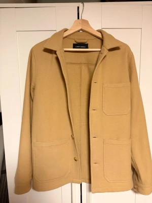 A days march beige ull overshirt - Stilren overshirt/jacka från A Day's March i tunn ull, perfekt för kyliga sommarkvallar. Schysst look och fin struktur i tyget. Perfekt för layering eller som lättare jacka. Skulle saga True to size Utmärkt skick utöver att lappen i nacken håller på att lossna, men absolut inget som märks eller syns vid anvandning. Skriv vid frågor! Pris är inte hugget i sten.