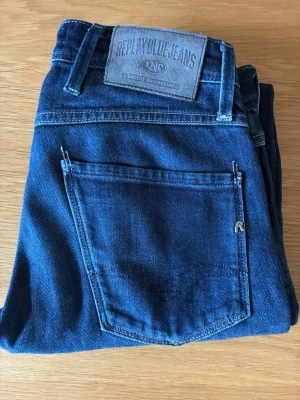 Mörkblå jeans från Replay - Snygga mörkblå jeans från Replay med klassisk femficksdesign och tydlig logotyp på bakfickan. Jeansen har en rak passform och är tillverkade i mjukt denimtyg som ger en skön känsla. Perfekta för dig som gillar stilrena och tidlösa jeans.