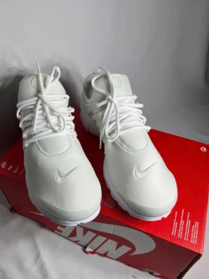 Nike presto vita Finns i 43 - Snygga helvita sneakers från Nike med broderad Swoosh på tån och klassisk siluett. Skorna har rund tå, vita skosnören och ovandel i textilmaterial. Perfekta för dig som gillar en clean och stilren look.