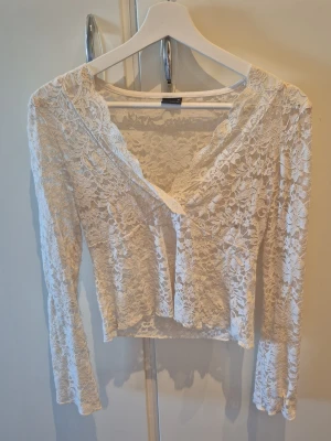 Vit spetsblus från Gina Tricot - Säljer en vit långärmad blus från Gina Tricot i spets. Blusen har v-ringning. Storlek M.
